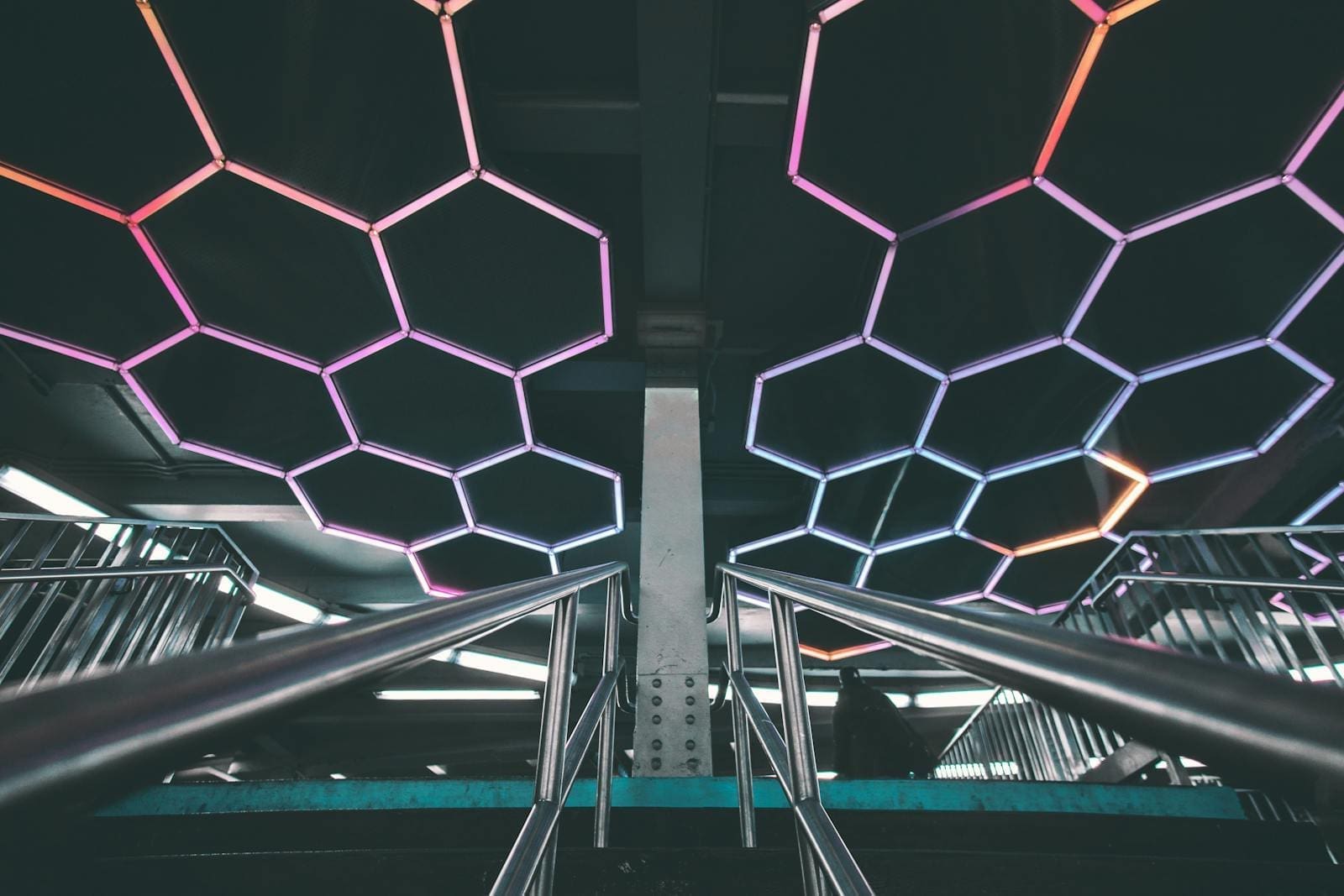Entrance to fintech marketplace with a futuristic design featuring illuminated geometric patterns and stainless steel railings.